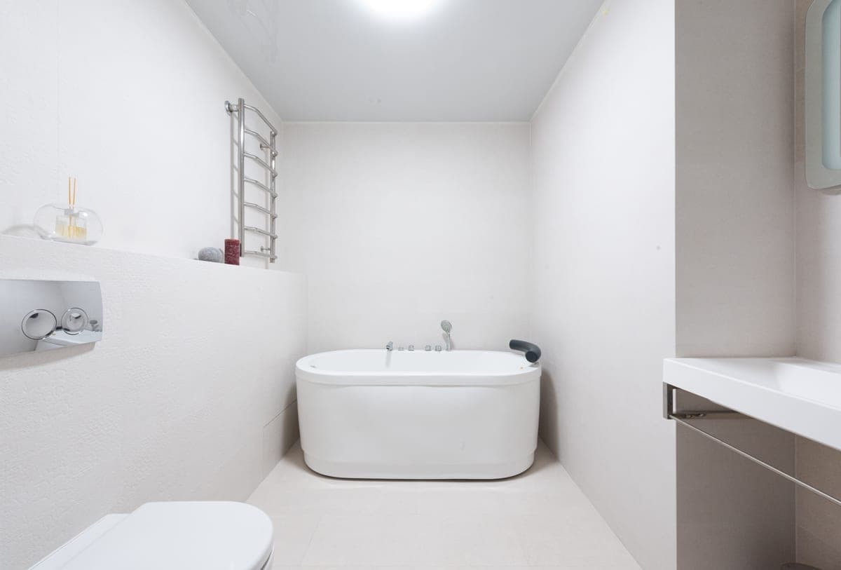 A white bathtub in a bright bathroom with a sink alongside