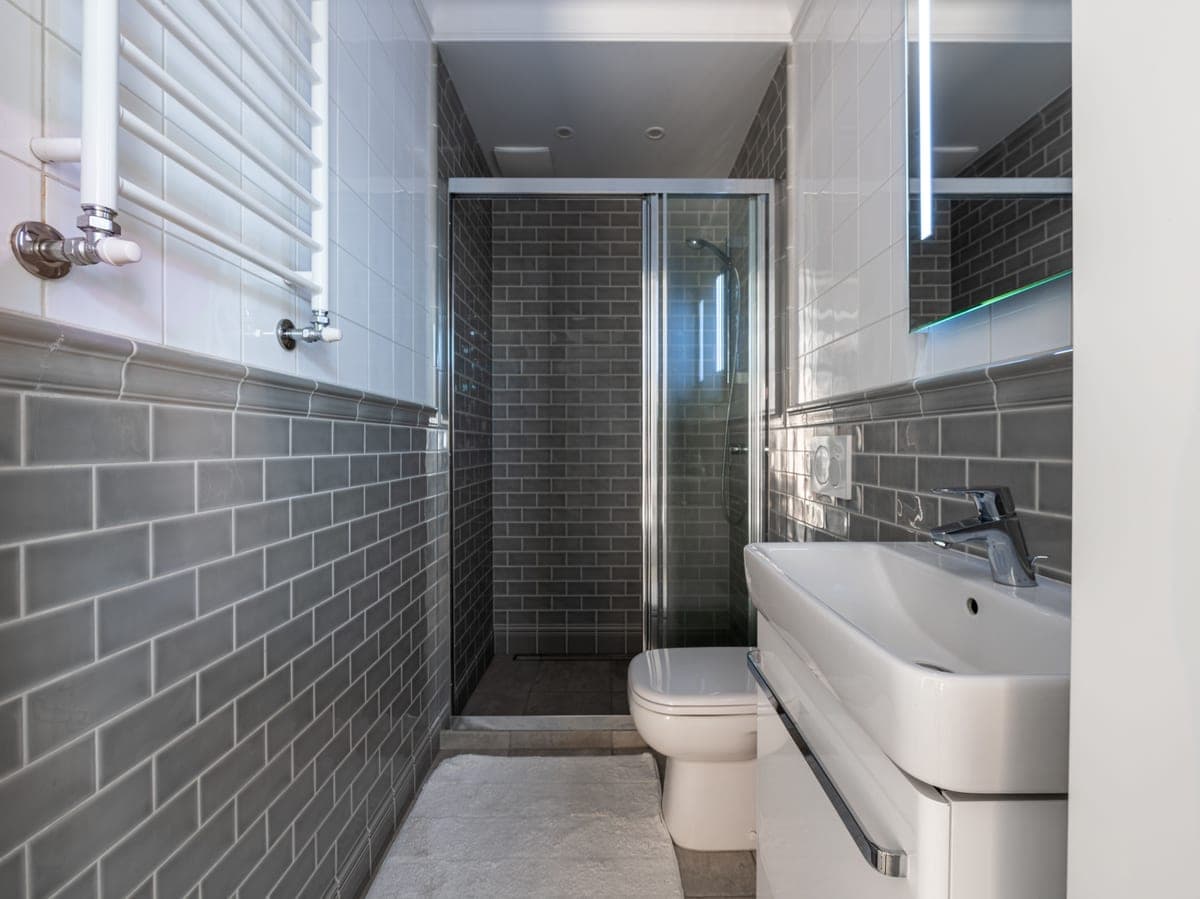 A spacious tiled shower in a bright bathroom