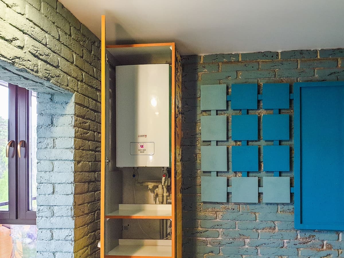 A storage water heater standing against a wall in a service space